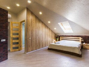 Un dormitorio con techo inclinado, armario de madera y tragaluz.