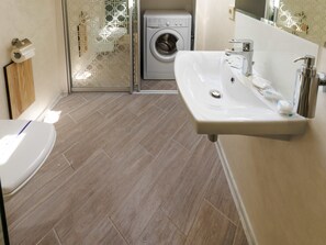 Un baño con inodoro, lavamanos y lavadora.