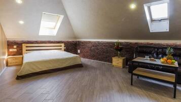 A bedroom with a sloped ceiling, a bed, a wooden bench, a small table with fruit, and a brick accent wall.