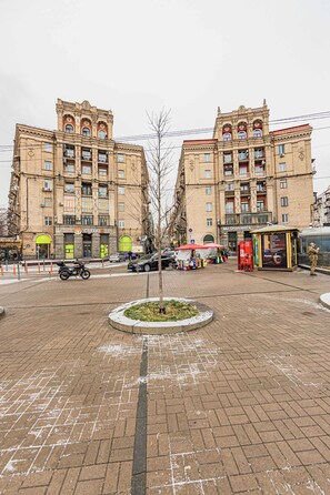 Un edificio grande con varios pisos y balcones, un restaurante McDonald's y una parada de autobús.