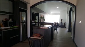 A modern kitchen with a central island, dark cabinetry, and a view into the dining area through an archway. - Hospedaje Solymar Islas (San Andrés)