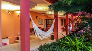 A spacious interior with a hammock, a staircase, and lush greenery. - Pousada Saudosa Maloca (Porto Seguro)