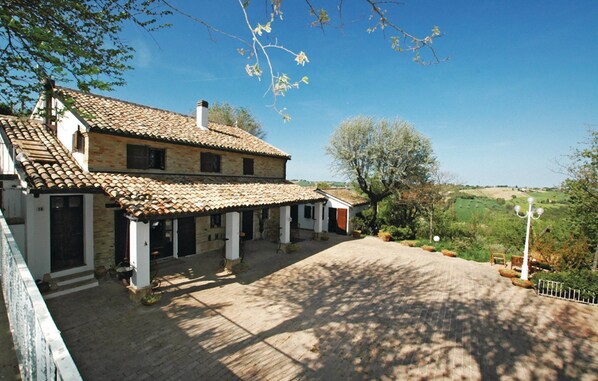A two-story house with a tiled roof, a covered patio, and a paved driveway.