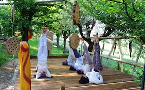 Un grupo de personas practicando yoga en una terraza de madera rodeada de árboles.