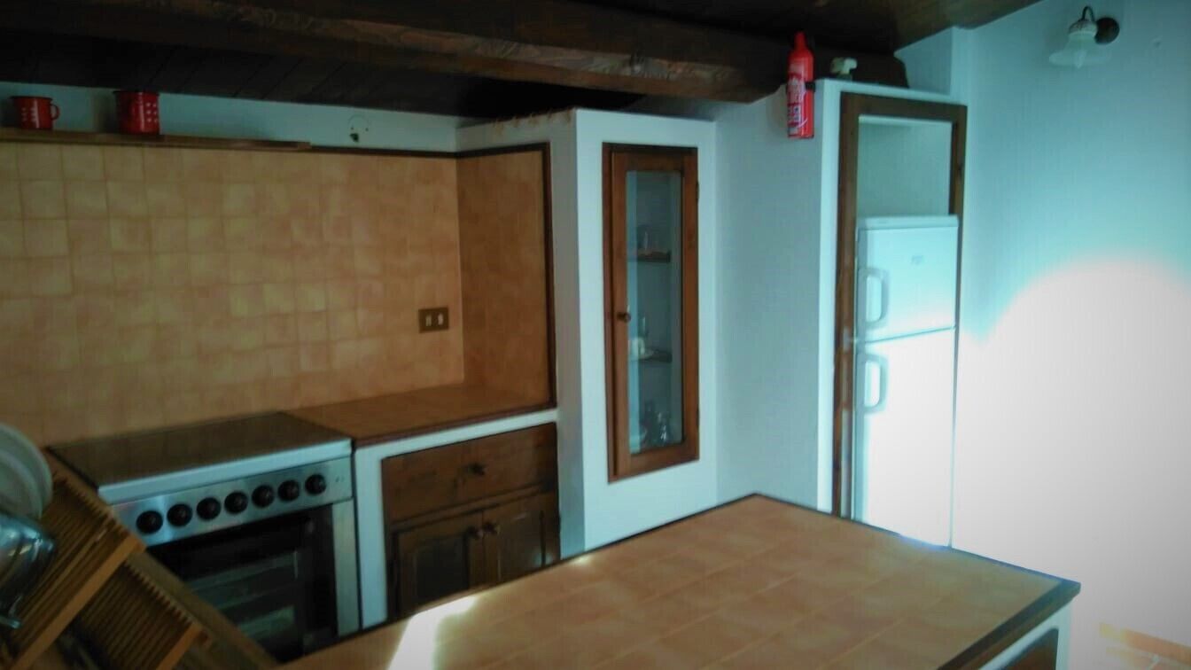 Eine kleine Küche mit Herd, Backofen und Kühlschrank.