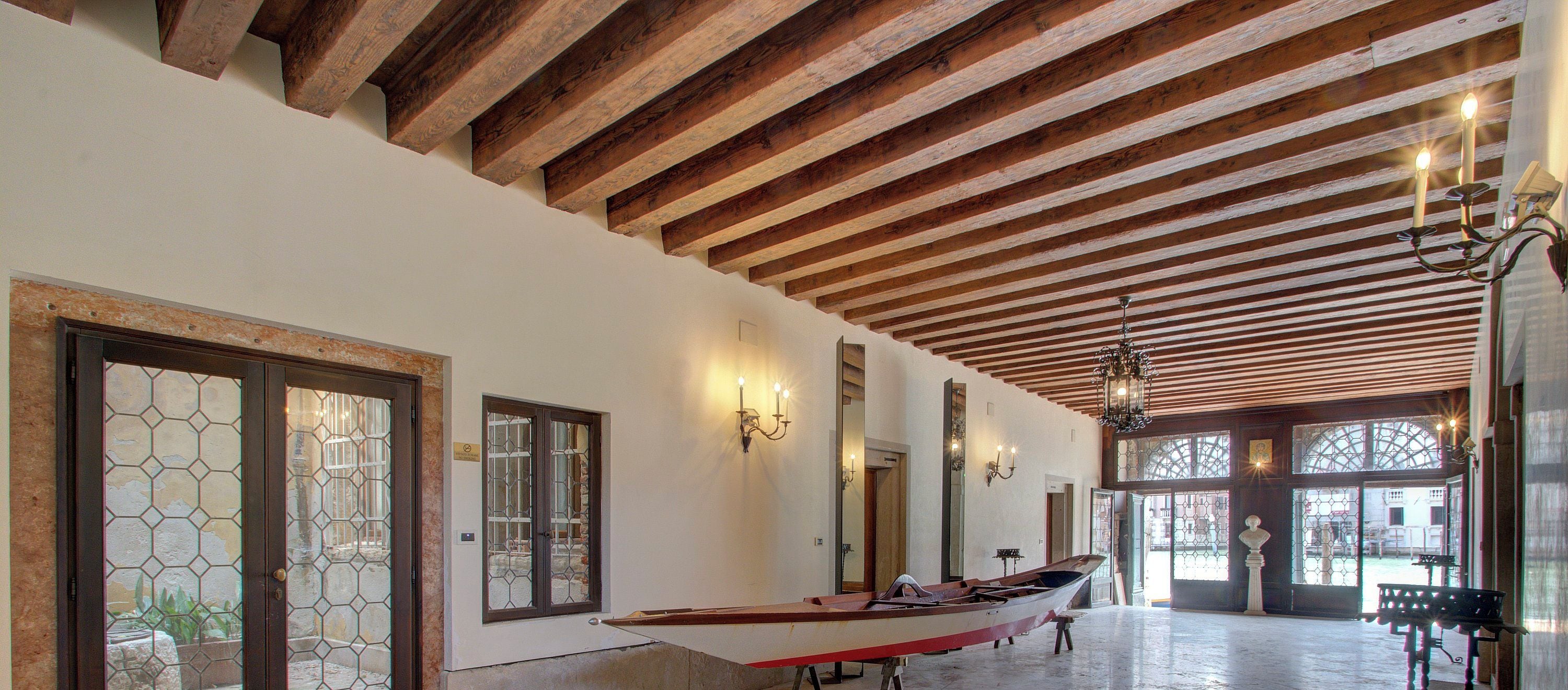 A spacious interior with a wooden ceiling, large windows, and a boat displayed against the wall.