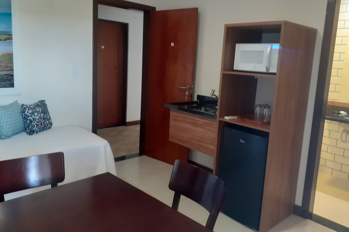 A hotel room with a bed, a desk, a microwave, and a small refrigerator.