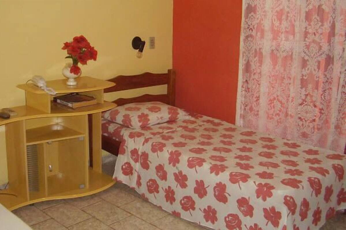 Une chambre à coucher avec un lit, une table de chevet avec une lampe et une petite armoire.