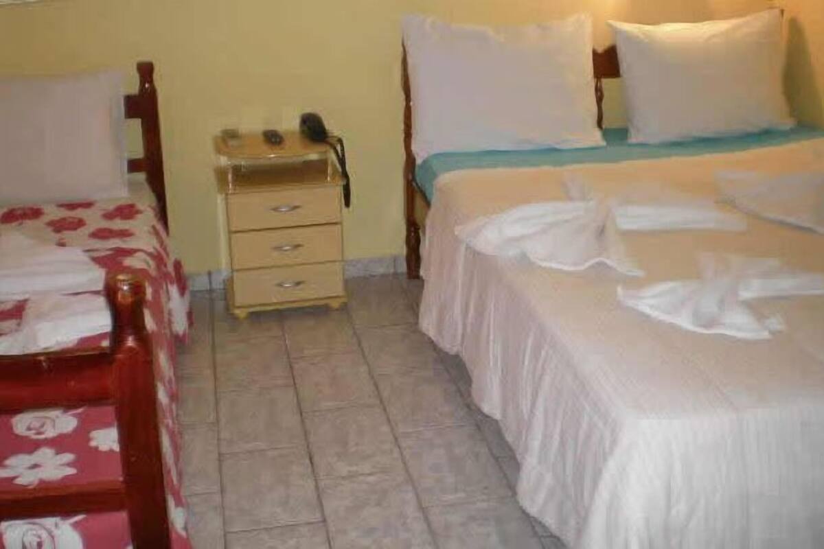 Une chambre d’hôtel avec deux lits, une table de chevet et une petite commode.