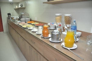 Un bufé con diversos alimentos, un dispensador de agua y una jarra de jugo.