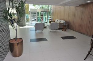 A lobby with a reception desk, seating area, and a large potted plant.
