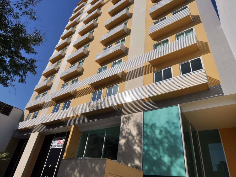 A multi-story building with balconies, large windows, and a staircase leading to the entrance.