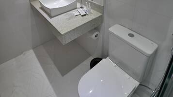 Un baño moderno con un lavabo, espejo y retrete blancos.