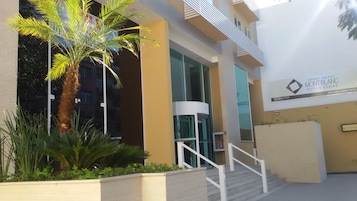 A modern building with a palm tree and a staircase leading to an entrance.