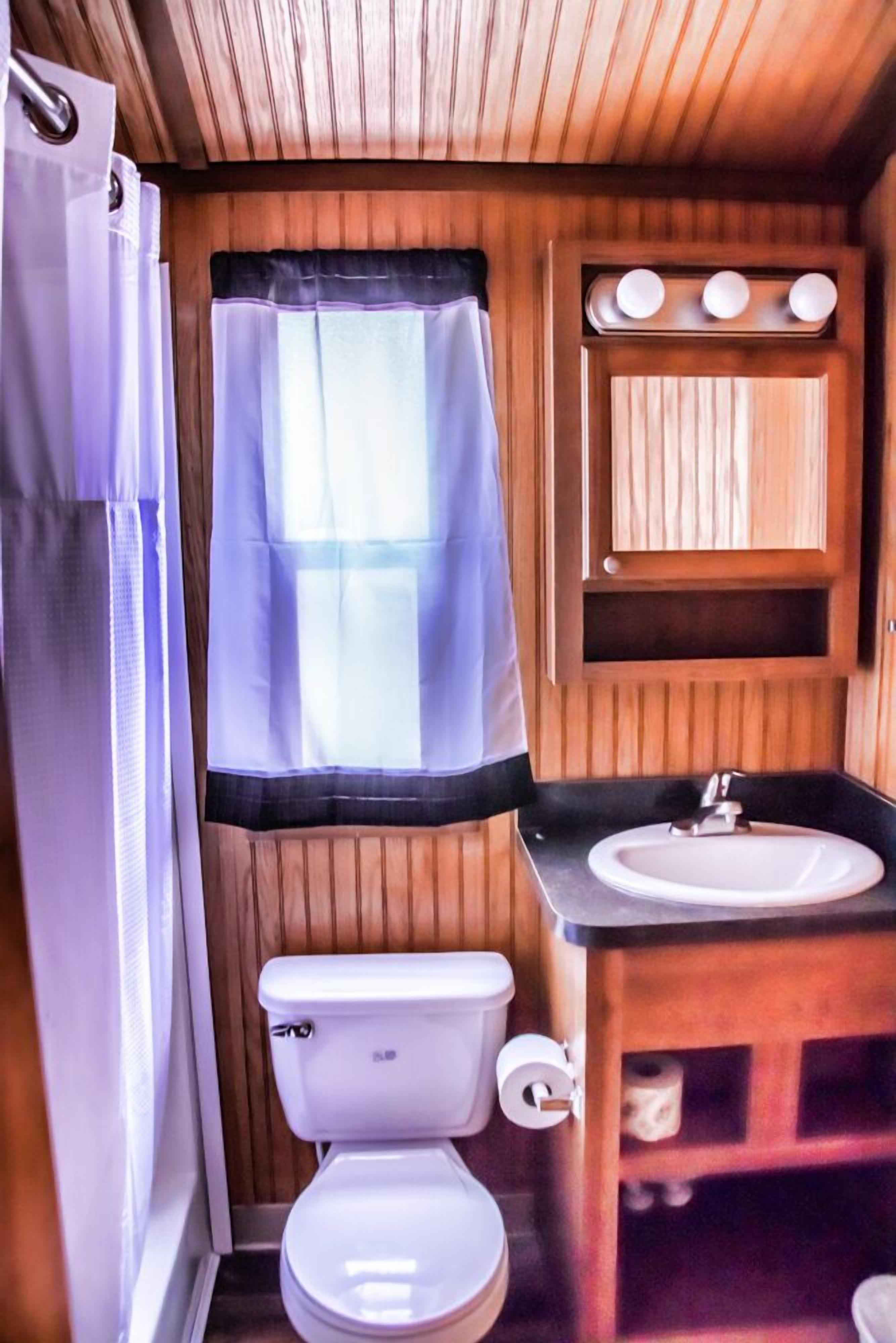 A compact bathroom with a toilet, sink, and wooden paneling.