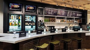 A bar area with a counter, multiple shelves of bottles, and a menu board.