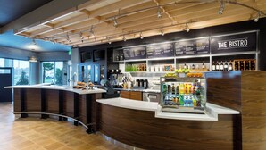 A modern bistro with a curved counter, a menu board, and a wine display.