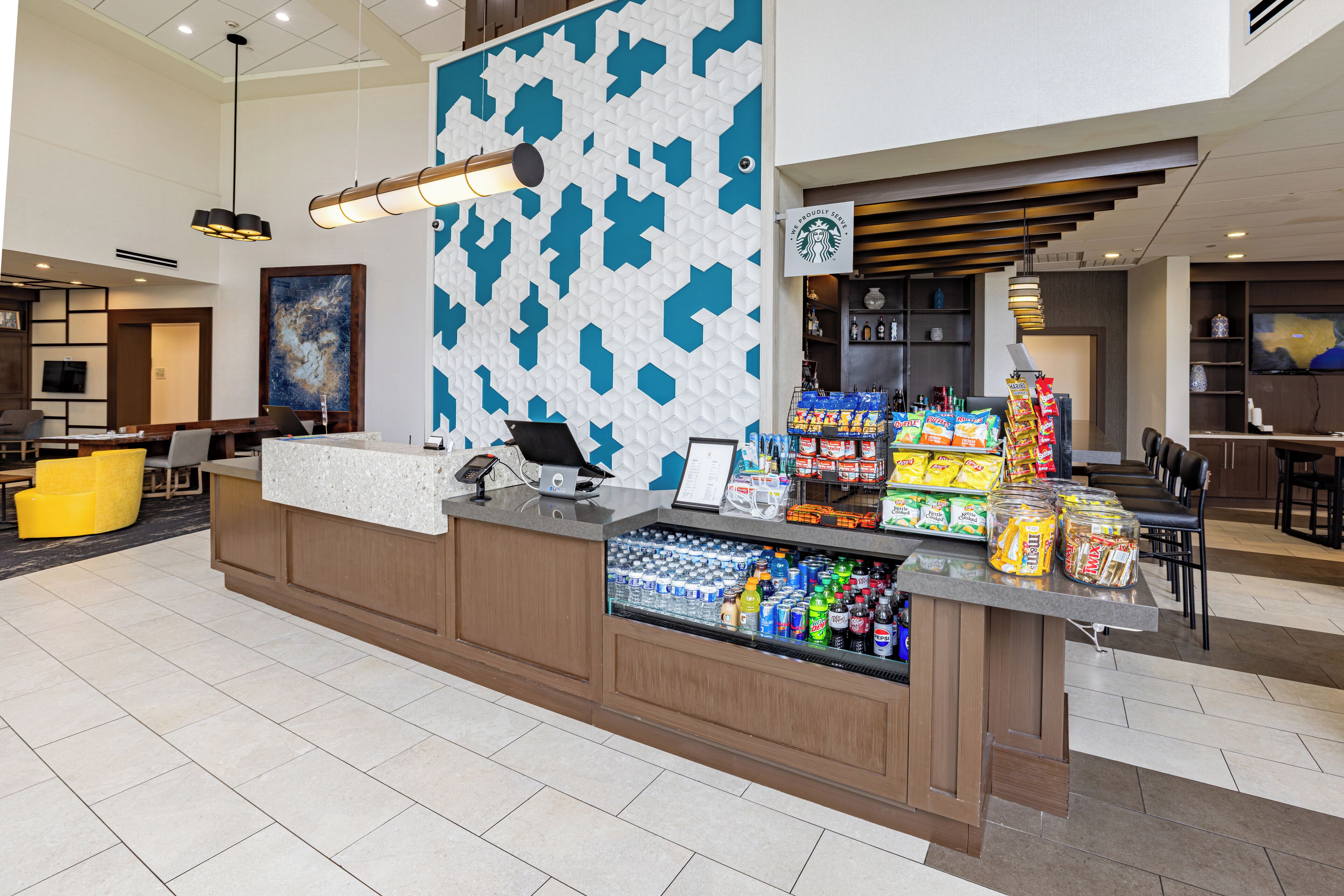 A hotel lobby with a reception desk, a Starbucks sign, and a snack bar.