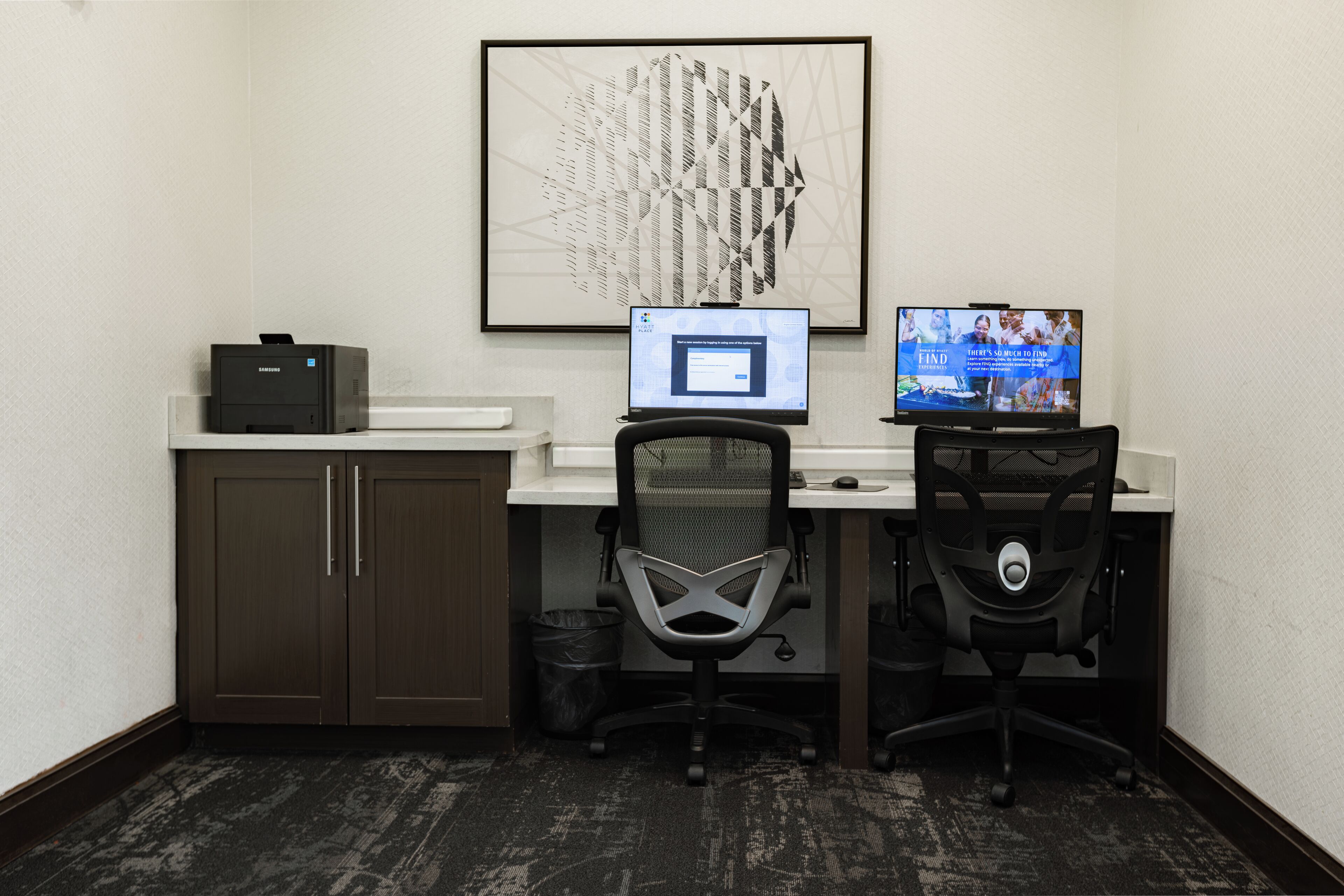A small office with two desks, one with a computer and a monitor, and a chair in front of it.