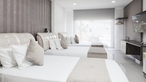 A modern hotel room with two large beds, a TV, and a large window.