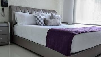 A modern bedroom with a bed, pillows, a nightstand, and a telephone.