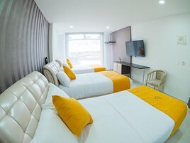 Habitación de hotel con dos camas, televisor, escritorio y una silla.