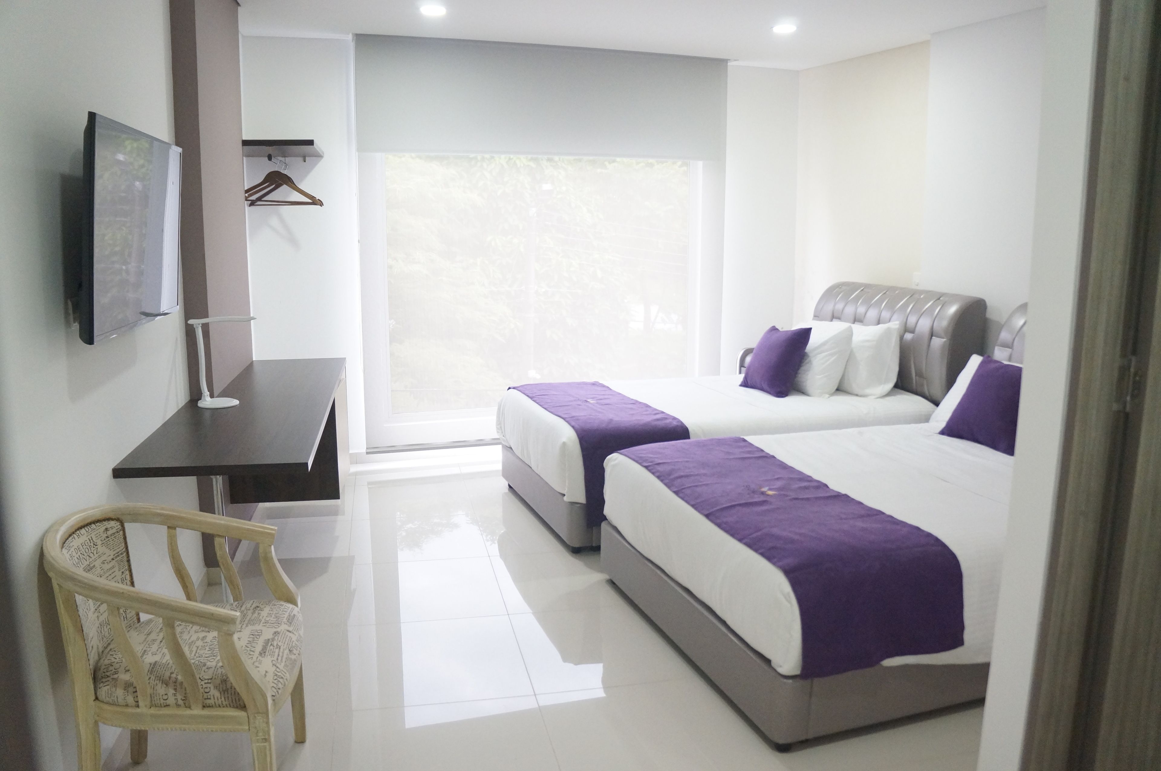 Una habitación de hotel con dos camas, un escritorio, una silla y un televisor.