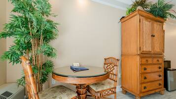 Quarto com uma mesa redonda, duas cadeiras, um armário e uma planta grande.