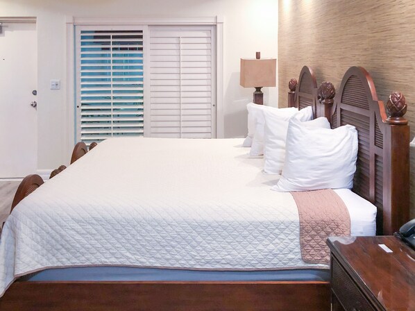 A neatly made bed with white linens, a wooden headboard, and a bedside table with a lamp.
