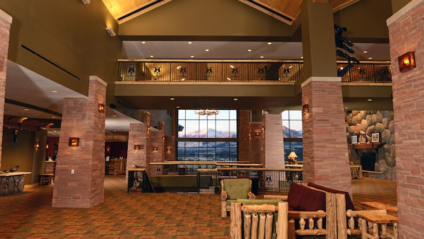 A spacious lobby with a high ceiling, wooden beams, and a view of mountains through large windows. - Great Wolf Lodge Colorado Springs (Colorado Springs)