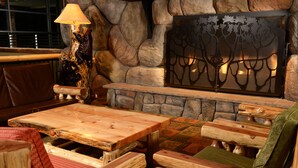 A rustic interior with a stone fireplace, wooden furniture, and a decorative metal tree panel. - Great Wolf Lodge Colorado Springs (Colorado Springs)