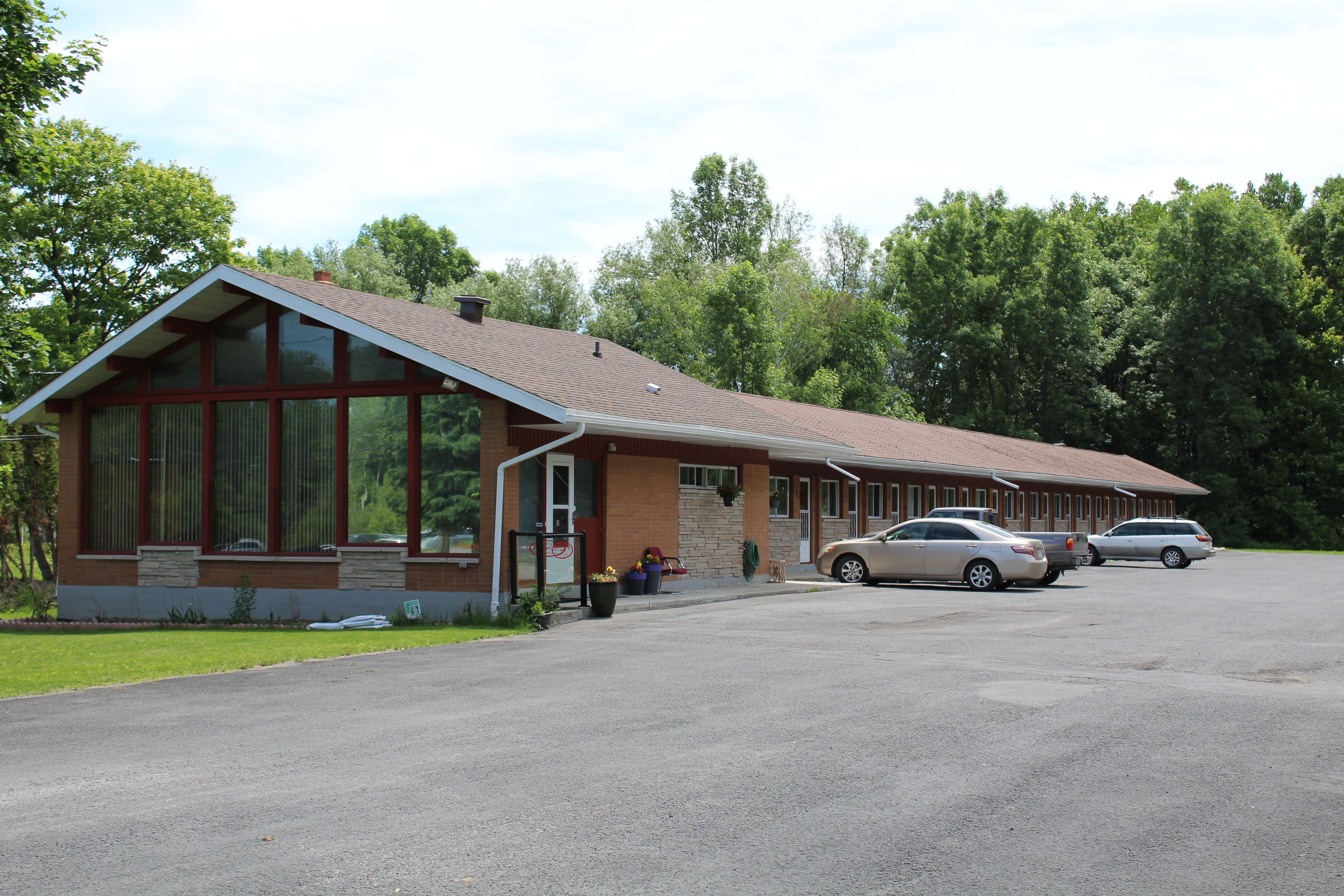 A building with a sloped roof and large windows, parking in front.