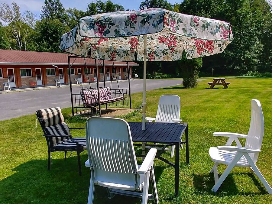 An outdoor seating area with a table and chairs, a swing set, and a covered picnic table.
