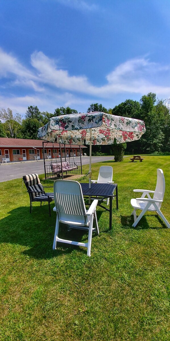 An outdoor seating area with a table and chairs, a swing set, and a covered picnic table.