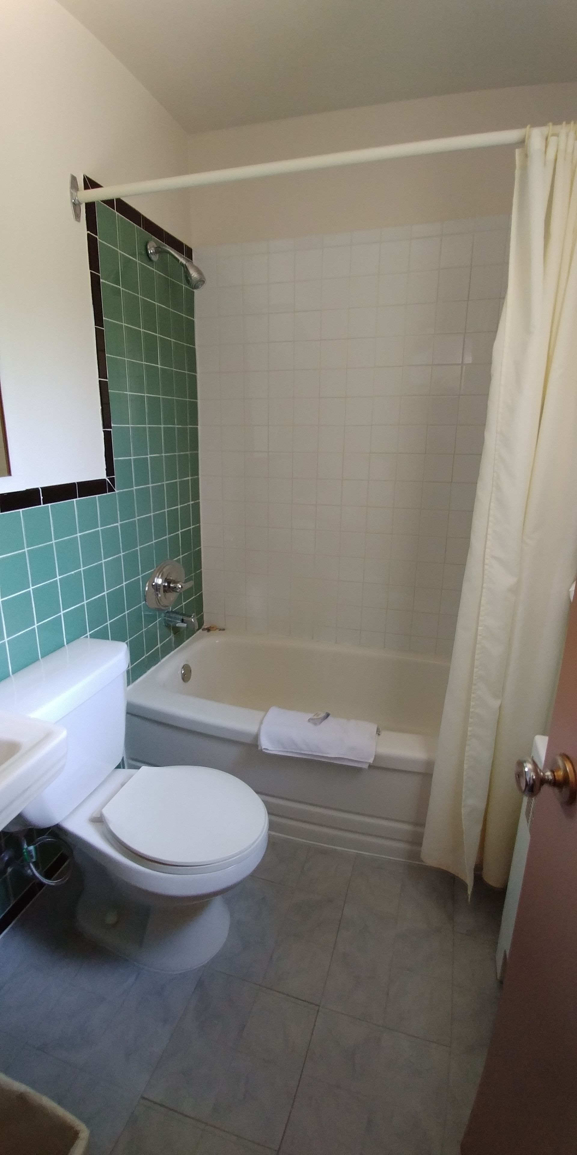 A bathroom with a toilet, sink, bathtub, and shower curtain.