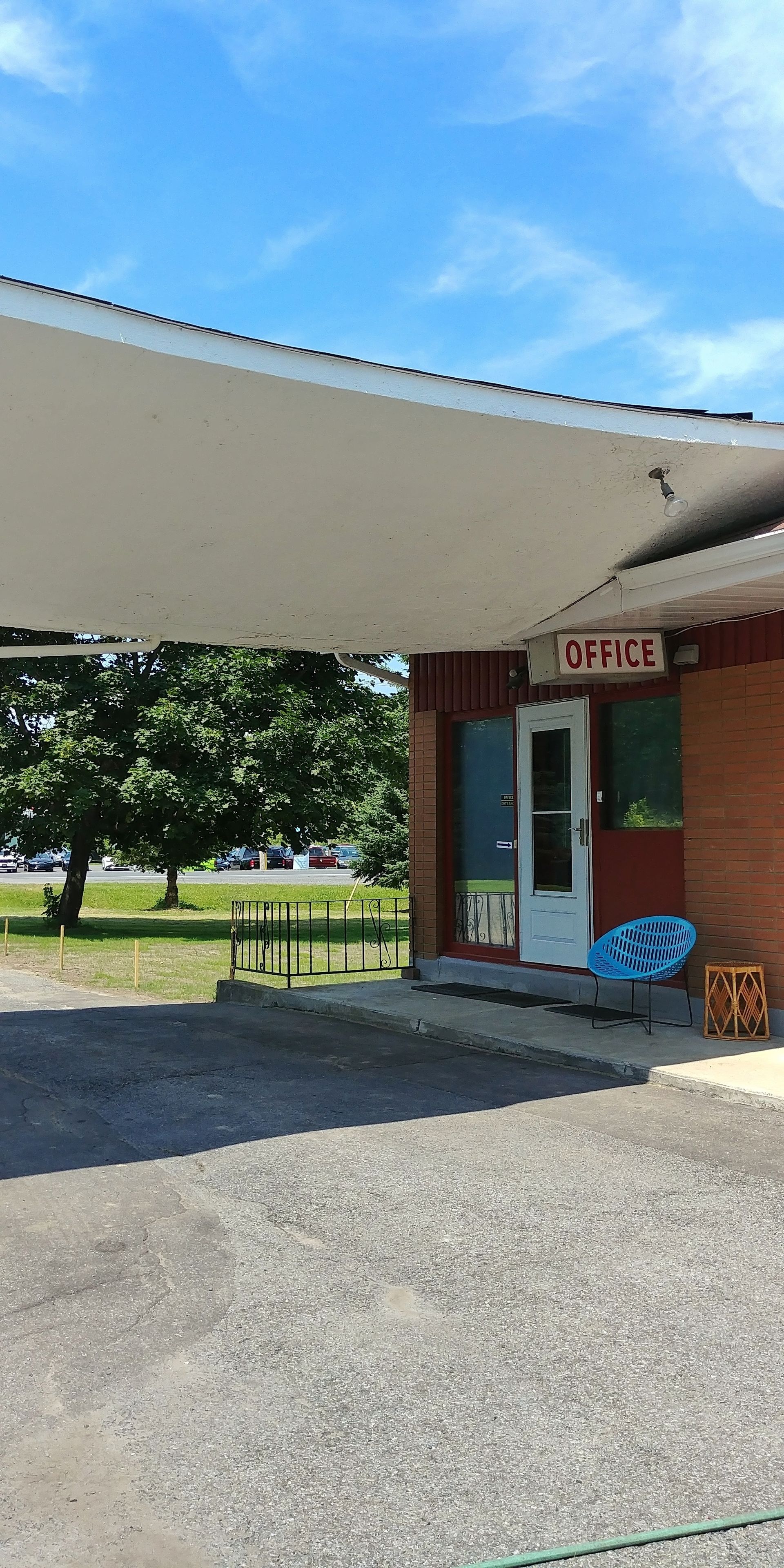 An office building with a sign reading "OFFICE" above the door, a blue chair, and a small table outside.
