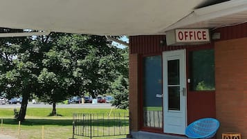 An office building with a sign reading "OFFICE" above the door, a blue chair, and a small table outside.