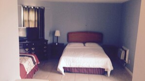 Ein Standard-Hotelzimmer mit einem Einzelbett, einem Schminktisch, einem Nachttisch, einer Lampe und einem Fernseher.