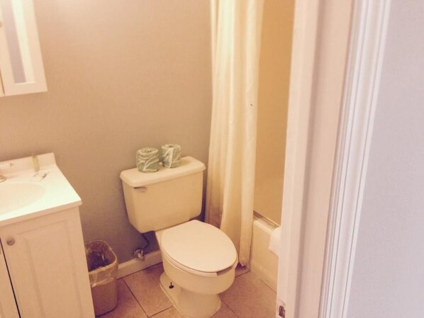 A small bathroom with a toilet, sink, and a trash bin.