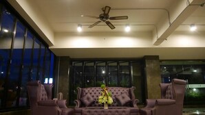 A lobby with a tufted sofa set, a ceiling fan, and large windows. - Green Garden Place (Udon Thani)