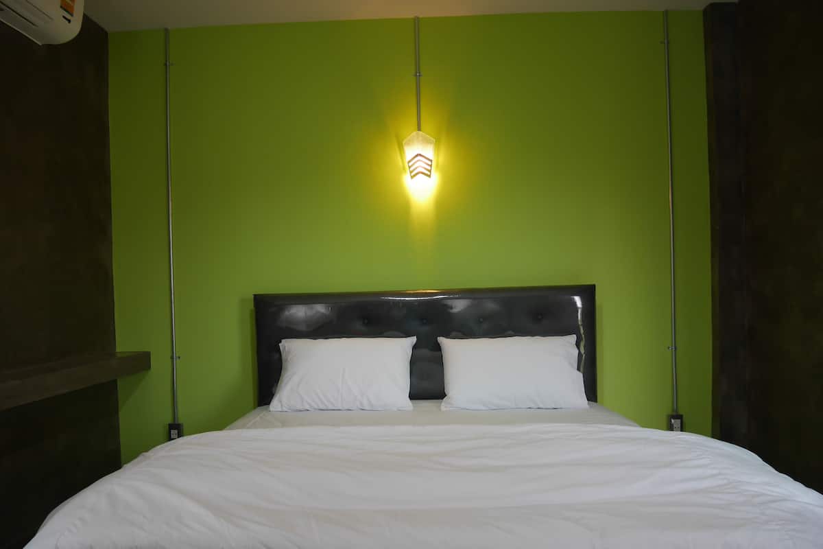 A bed with white bedding in a room with green walls and a black headboard.