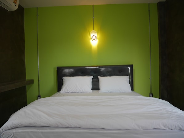 A bed with white bedding in a room with green walls and a black headboard.