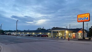 A motel with a large sign, a parking lot, and several cars parked in front. - Economy Inn (McCook)