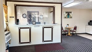 A reception area with a 'Welcome' sign, a small table with chairs, and a microwave in the background. - Economy Inn (McCook)