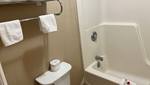 A bathroom with a bathtub, toilet, and towel rack. - Economy Inn (McCook)