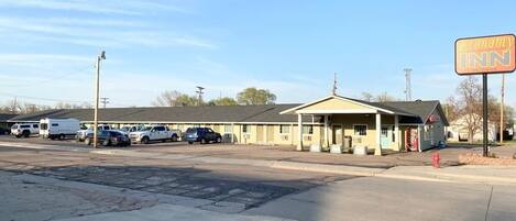 A motel with a yellow exterior, a covered parking area, and a sign for 'Economy Inn'.