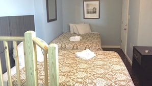 A bedroom with two beds, a wooden headboard, a framed picture on the wall, and a door. - HC-55 Beach Haus (Seaside Heights)
