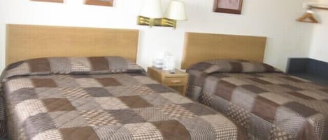 Habitación doble con dos camas, una mesita de noche con lámpara y cuadros en la pared.