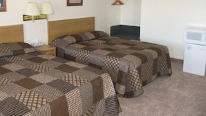 A hotel room with two beds, a nightstand, a desk, a chair, a microwave, and a wall-mounted lamp. - Little Bear Motel (Green River)
