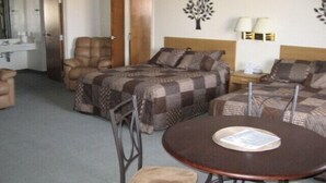 A hotel room with a bed, a chair, a table, and a nightstand. - Little Bear Motel (Green River)